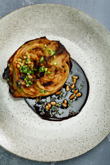 Grilled cabbage served with sauce and pine nuts. Delicious vegetarian food. Dark moody style.