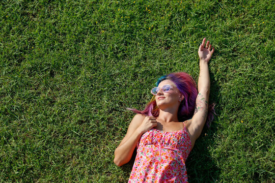 Smiling woman lying on grass enjoying sunny day