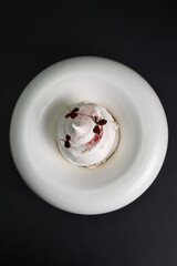 Pavlova dessert in white bowl over black background. Meringue dessert.