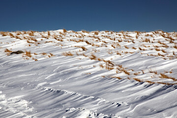 Abstract winter background of frozen snow in the mountains and blue sky