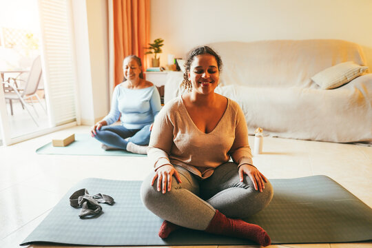 Mother And Daughter Doing Yoga Exercises At Home Together During Winter Time - Focus On Girl Face