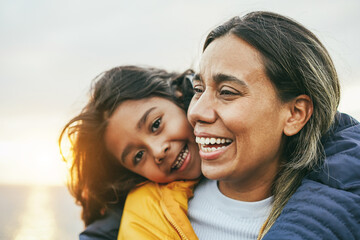 Happy latin mother and daughter having fun during winter time - Mom day and family love concept -...