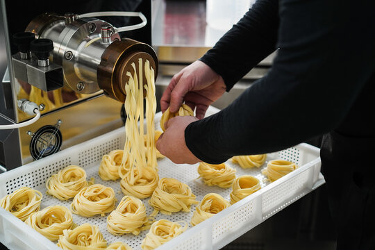 Man working with pasta manufacture machine while doing italian style tagliatelle 