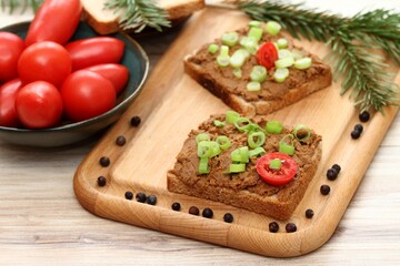 Pate spread from deer meat on whole grain bread  and green onion. Sandwich with meat pate on cutting board, fresh tomatoes and spices for venison around. Decorated with spruce branch.