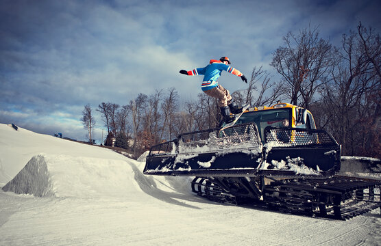 Snowboarder grinding on snowcat blade