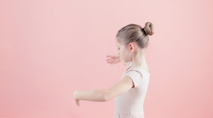 little ballerina making a dance moves on a pink background with copy-space