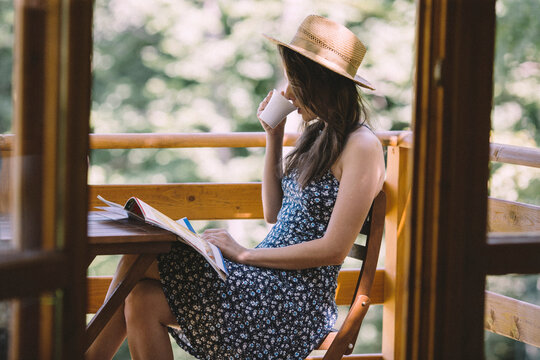 Woman drinking coffee and reading newspapers on balcony