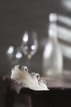 Wine glasses on the table and a beautiful white feather. Romantic date