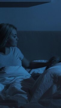 Apnea insomnia. Stressful couple night. Sleep disorder. Tired disturbed wife in bed with snoring husband late in dark bedroom. Vertical video.