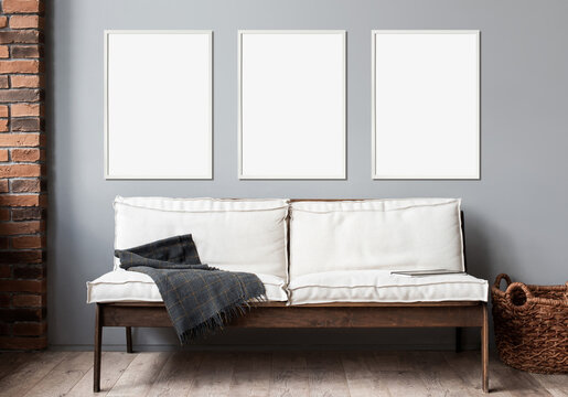 Blank picture frame mockup on gray wall. Modern living room design. View of modern scandinavian rustic style interior with sofa. Three vertical templates for artwork, painting, photo or poster