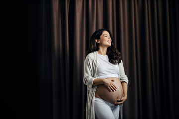 Portrait of a pregnant woman caressing her belly and waiting for a baby.