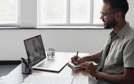 Smiling Black Man Has Video Call Conference With His Remote Teammate. Young Student Men Learning Online. Businessman Working On Laptop Computer Indoors