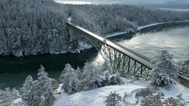 Wide aerial view of Deception Pass Bridge on Whidbey Island with snow covering the ground.