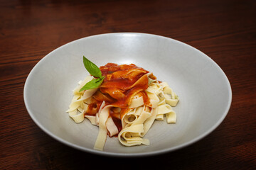 Pasta fresca  artesanal, fettuccine al basilico - tallarines de albahaca fresca caseros hechos a mano en casa servidos en plato