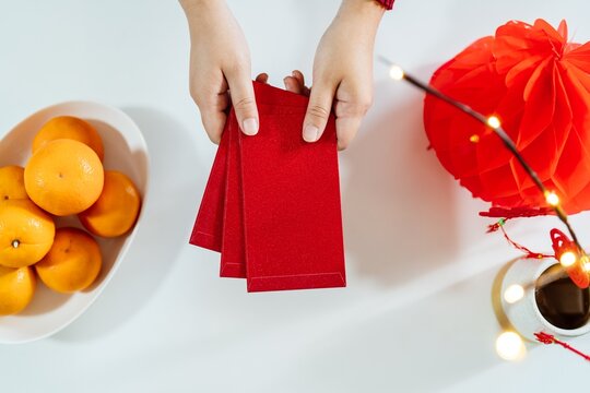 Asian Woman giving red envelope for Lunar New Year celebrations. Hand hold red packet