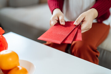 Asian Woman giving red envelope for Lunar New Year celebrations. Hand hold red packet