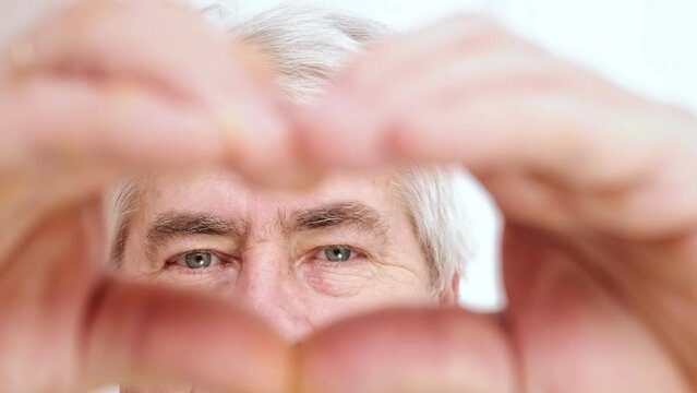 Happy Old Senior Man Making Heart Shape Hand Gesture. Look at Camera, Showing Romantic. Retired Elderly Grandparent Close Up Portrait. Symbol of Love Yourself. Doing charity Work, take Care of Health.