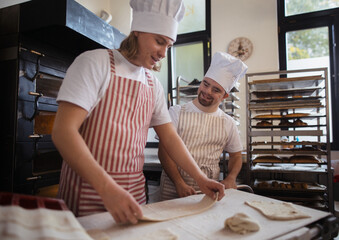 Man with down syndrom helping prepair bread in bakery with his colleague. Concept of integration...