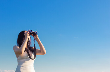 young girl with binocular on background blue sky