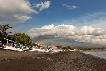 Fototapeta na wymiar Beautiful rainbow over Agung volcano on sunny day Amed beach Bali Indonesia