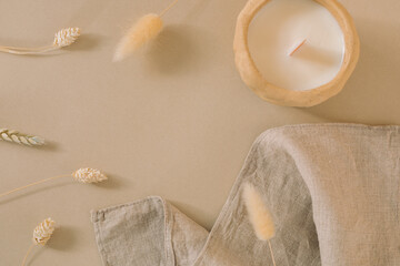 Still life of dried grass, napkin, candle on beige background with copy space. Minimalistic textured natural composition.