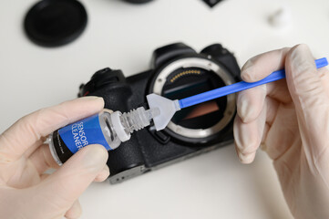 Hands holding sensor cleaning swab and applying a special cleaner to clean the camera sensor. Cleaning and maintaining the mirrorless camera sensor.Care for professional photographic equipment.