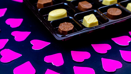delicious chocolate surrounded by pink hearts on black background