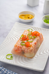 Fish aspic of shrimp, salmon and boiled quail eggs garnished with red caviar and green onions on a...