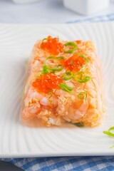 Fish aspic of shrimp, salmon and boiled quail eggs garnished with red caviar and green onions on a...