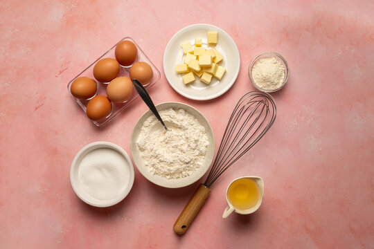 Food ingredients for baking eggs, flour, butter, oil and milk. Top view pink background.