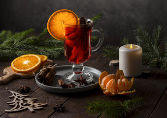 Christmas mulled wine and tangerines on a wooden table. Fir branches and a candle create a holiday...