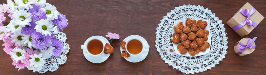 Freshly baked homemade heart-shaped cookies on lace hand-crocheted doily, bouquet of chrysanthemums...