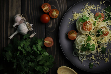 delicious fragrant pasta with grated cheese, red tomatoes, kenza greens and garlic on black plates and a wooden surface. for signboards splash screens labels banners menu flyers announcements