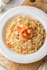 Risotto with prawns, salmon, leek and tangerine. Rice dish. White plate on a light background.  Directly above.