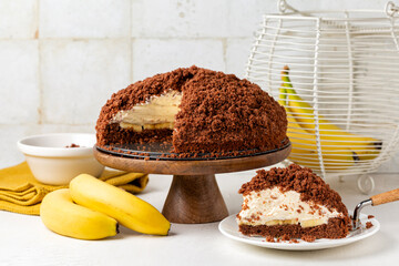 Homemade german mole cake with bananas, or maulwurfkuchen. Chocolate cake coat with crumbs, whipped...