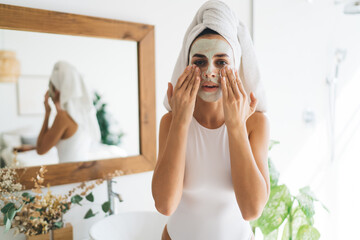 Woman applying eye patches before shower near mirror