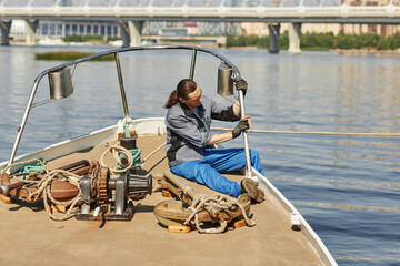 Wide angle view of sailor cleaning and repairing boat, scene lit by sunlight, copy space