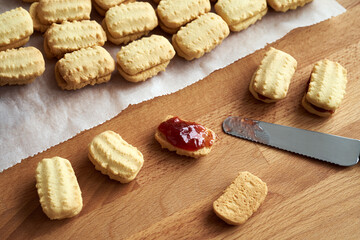 Filling traditional Christmas cookies with red strawberry marmalade