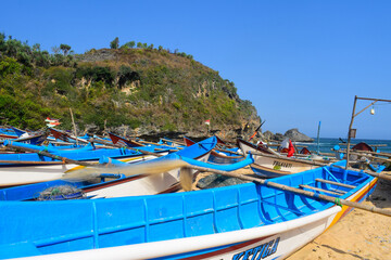 The view of white sand beach with blue sky view and fishing boat leaning on the beach