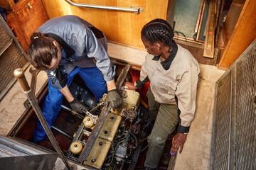 Fototapeta na wymiar Top view of two people repairing boat engine in pit, copy space