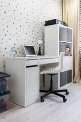 A workplace for a child with a table, a laptop and a table lamp in a modern apartment