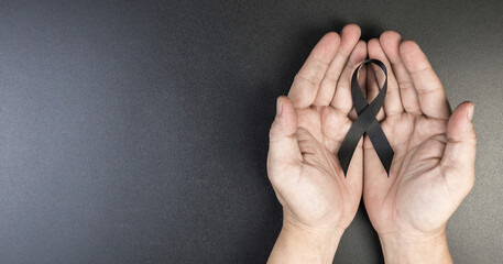 Hand hold black ribbon on background.
Bereavement and Mourning is the grieving process concept.