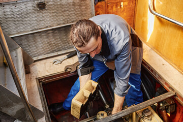 Fototapeta premium Portrait of male worker repairing boat engine in docks, copy space