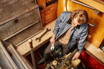 Fototapeta na wymiar Vibrant high angle portrait of man repairing boat engine in docks, copy space