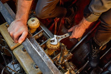 Close up of unrecognizable worker repairing engine and unscrewing bolts with metal wrench, copy...