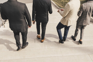 Fototapeta na wymiar A group of business men in suits descends the city stairs. outdoors. Working break. Collaboration and Teamwork