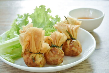 Kratong Thong Thai food made from fried mashed pork stuffed in dumpling flour with lettuce on plate dipping sweet sauce