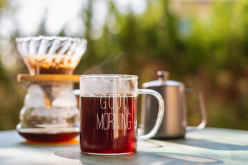 Hot drip coffee in glass coffee cup with morning sunlight.