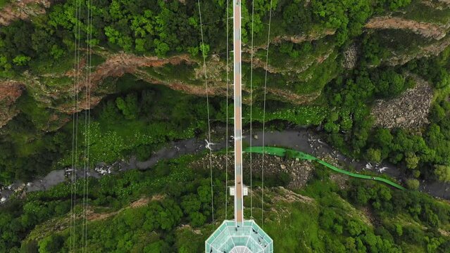 Dashbashi, Georgia - 19th june, 2022: Aerial fly over Diamond shape unique glass bridge over scenic dashbashi valley in Georgia countryside. Famous modern bridge over valley