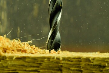 Macro image of the drill bit. Rotating drill bit and flying wood chips. Concept for woodworkers,...